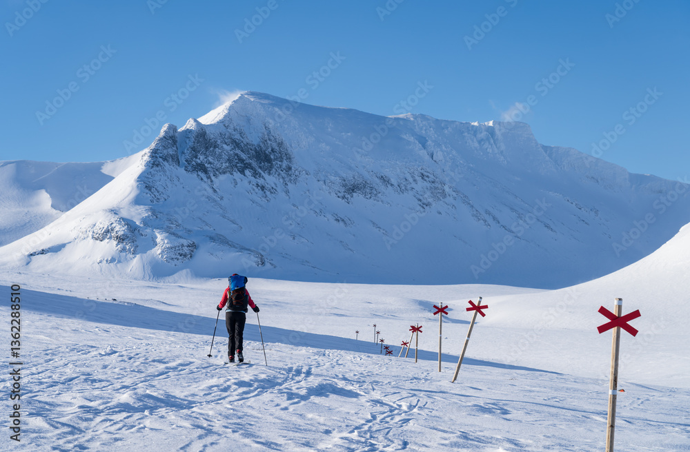 Woman cross-country skiing toward mountain Templet, in the Sylarna mountain range. Sweden.