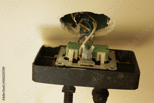 An electrical outlet with the front part unscrewed. A broken socket with protruding wires, electrical wiring repair