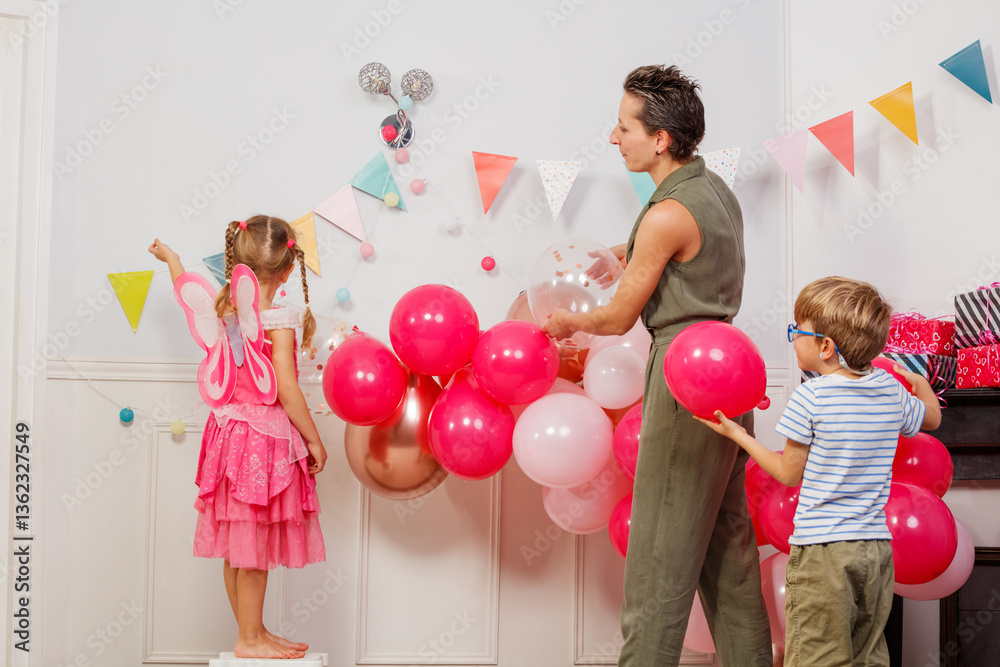 Family with kids decorate room in pink for girl birthday party