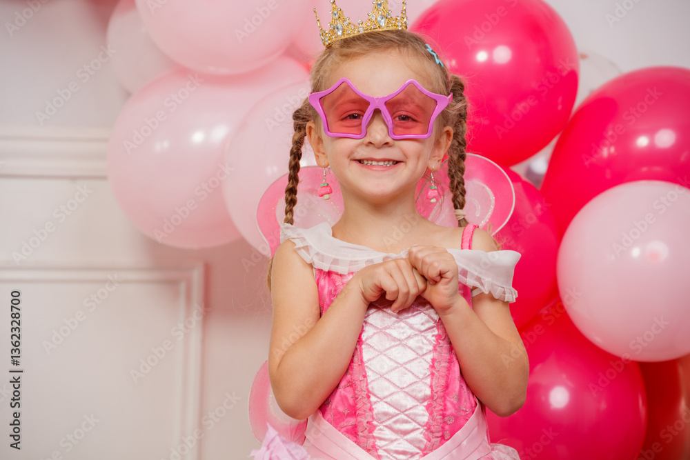 Little girl beaming in pink star glasses and princess rose dress