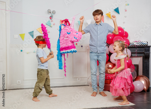 Young boy with blindfold prepare to hit colorful pinata unicorn