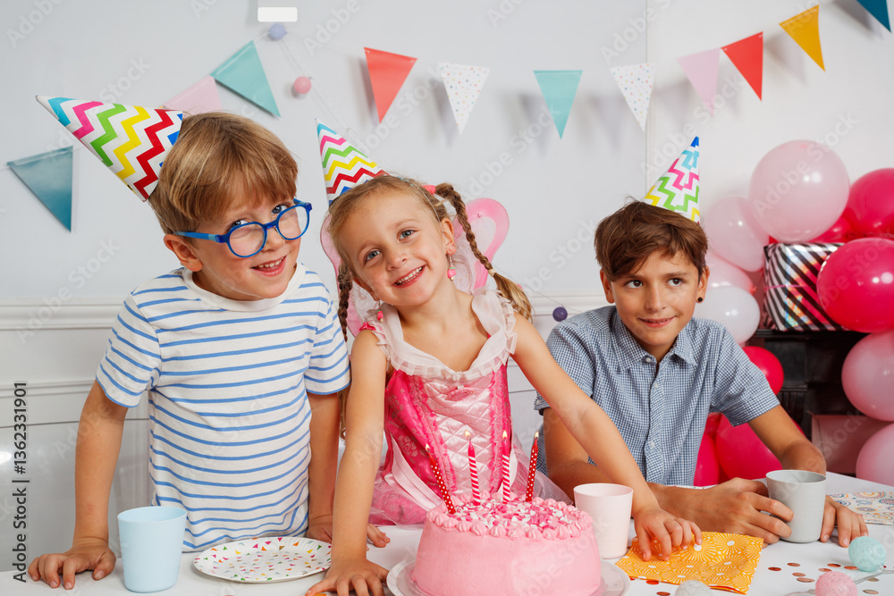 Kids enjoy a birthday party with pink cake and colorful hats