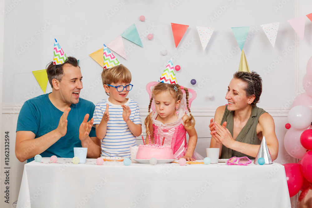 Happy family celebrates child's birthday with pink icing cake