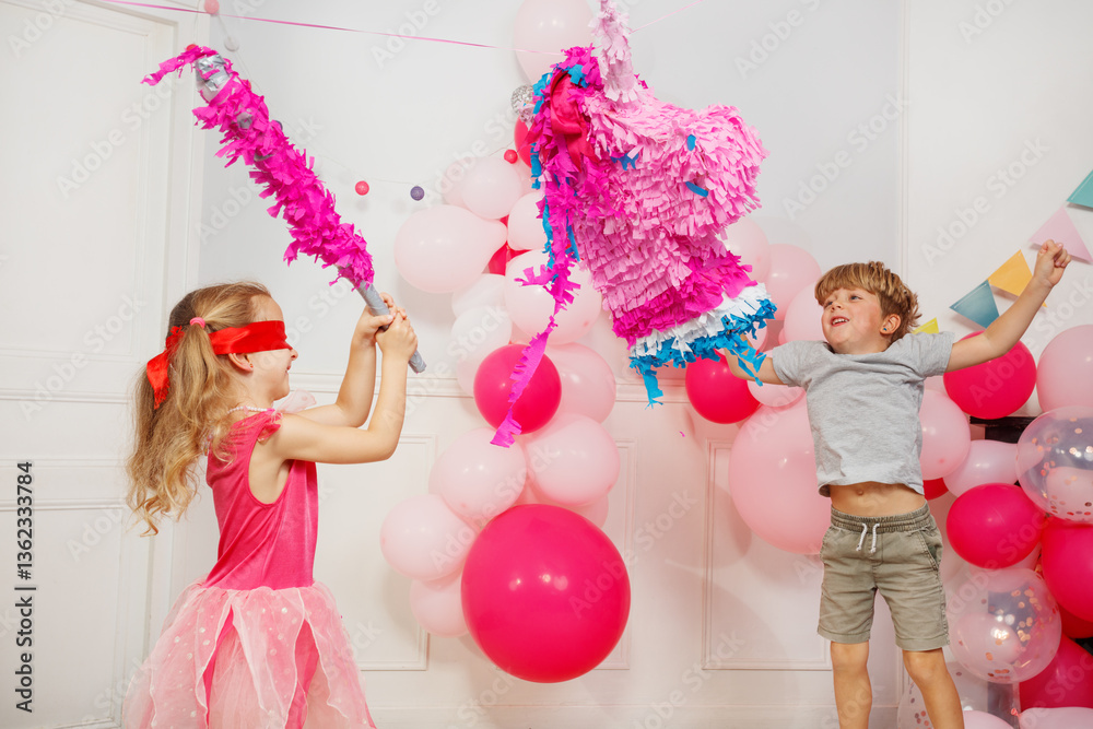 Children playfully hit and swing unicorn pinata having party fun