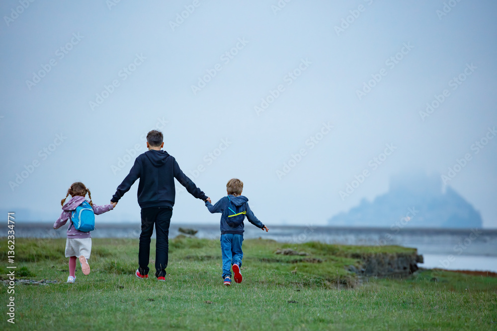 Little adventurers stroll across field, aiming for misty island