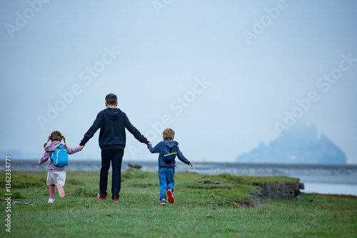 Obraz na płótnie Little adventurers stroll across field, aiming for misty island w salonie