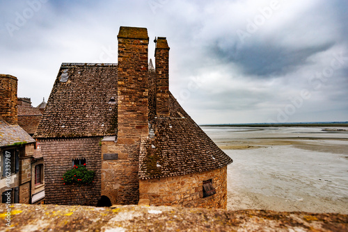 Obraz na płótnie Old stone castle wall of Mont Saint Michel beside sandy shore w salonie