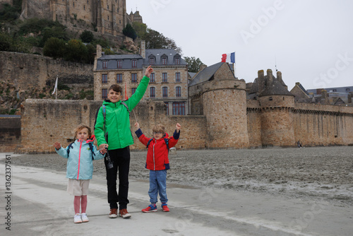 Obraz na płótnie Three kids pose excitedly near historic stone Mont Saint Michel w salonie