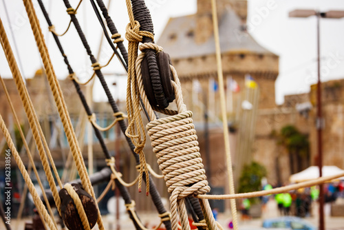 Obraz na płótnie Close-up of ship ropes with blurry historic tower in Saint Malo w salonie
