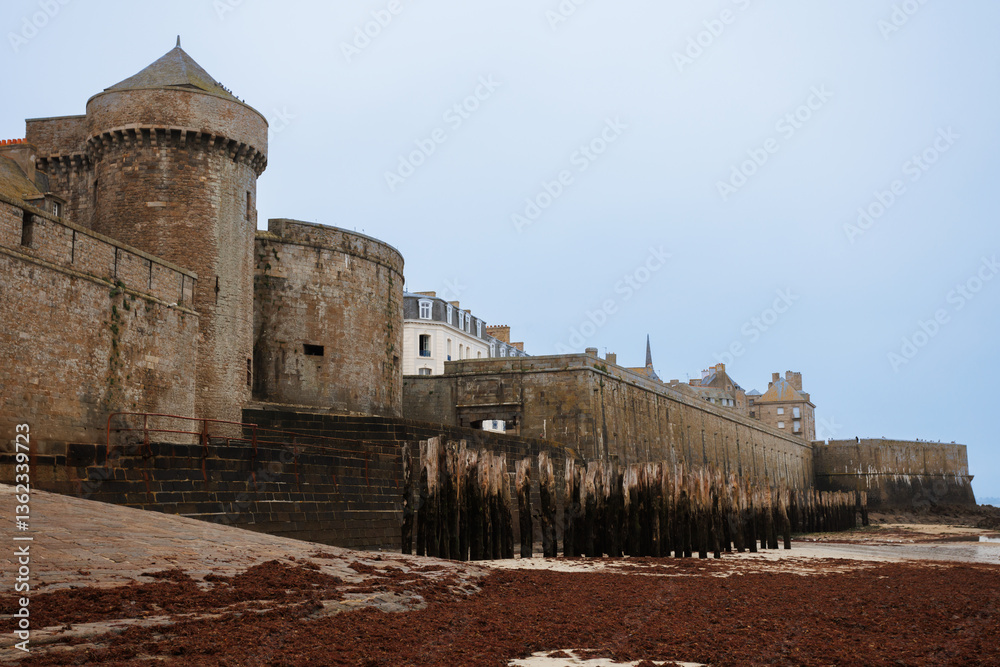 Medieval coastal fortress towers over sandy shoreline and ocean