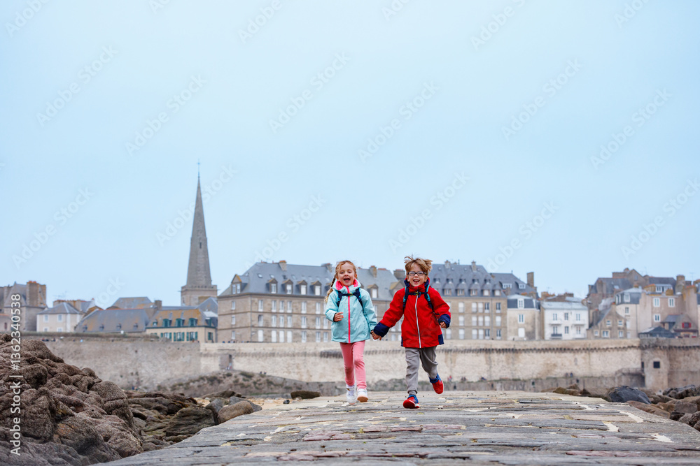 Children enjoying joyful run on a seaside walkway during tide