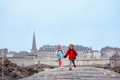 Obraz na płótnie Children enjoying joyful run on a seaside walkway during tide w salonie