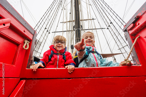 Obraz na płótnie Excited children tourists aboard red ship, pointing and laughing w salonie