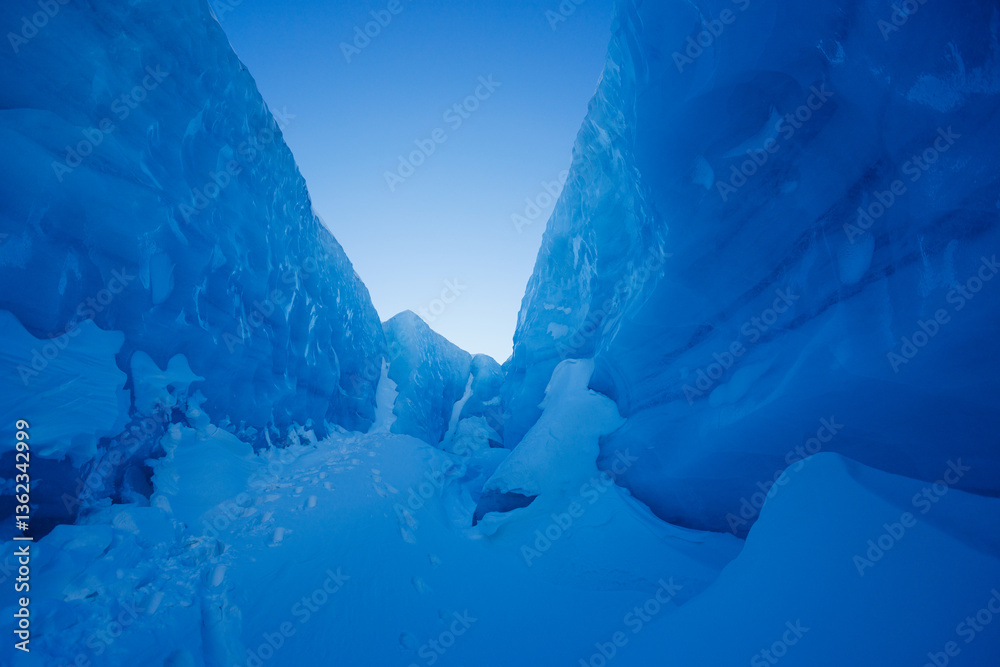 A wonder of serene blue icy glacier tunnel at snowy mountain