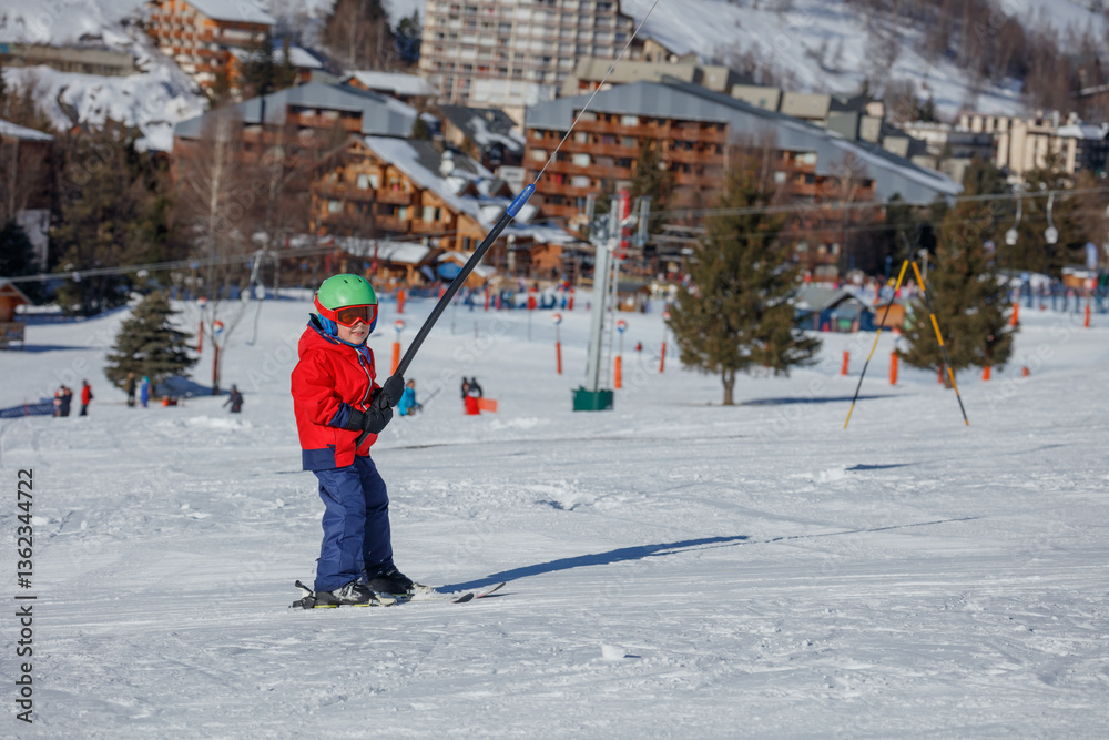 Child ascend on tow lift at sunny day in a mountain resort area