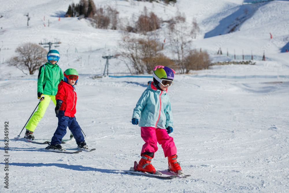 Three young skiers boys and girl hit the slopes on a sunny day