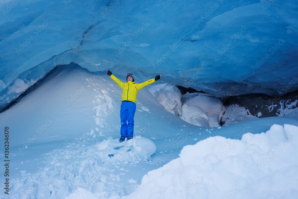 Skier man exploring a stunning blue ice cave in bright attire