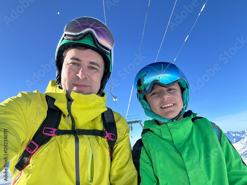 Obraz na płótnie Skiers dad and son enjoy sunny day on slopes in colorful gear w salonie