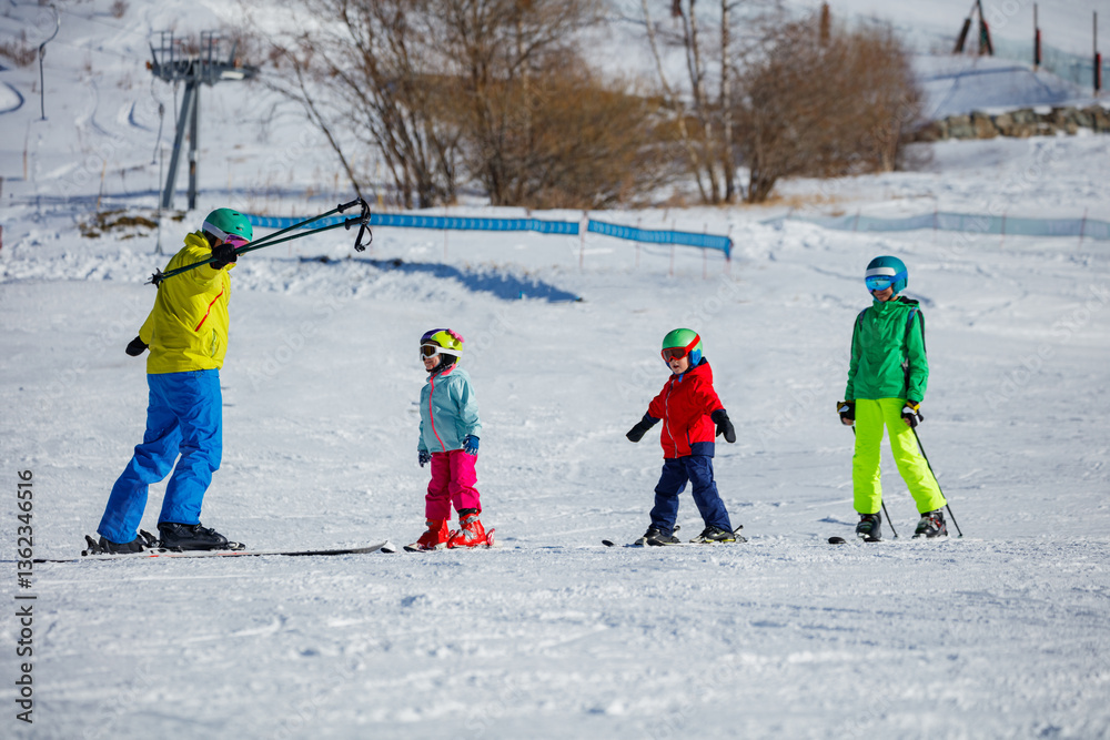 Ski coach accompany group of children, all on skis, skiing down