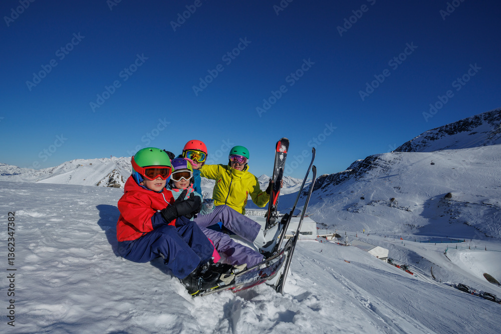 Group with kids waving hands rest of skiing in snowy mountain