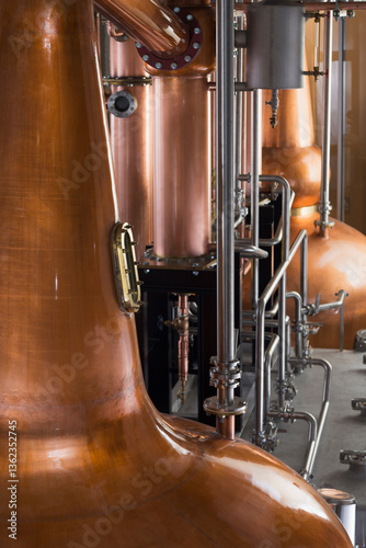 A copper still in a distillery, a large copper chamber and pipework for distilling. 