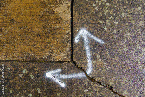Spray painted arrows on broken pavement