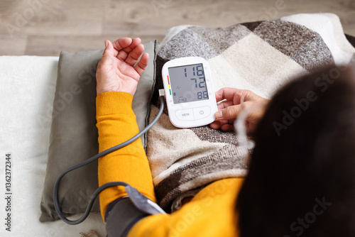 Senior woman measuring her blood pressure. Retired uses medicine digital device tonometer for control health at home