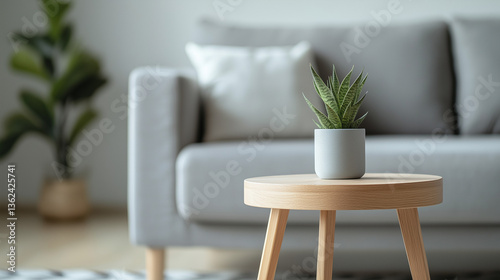Modern living room with grey couch and wooden table, soft light, minimalistic design, blurred background.

