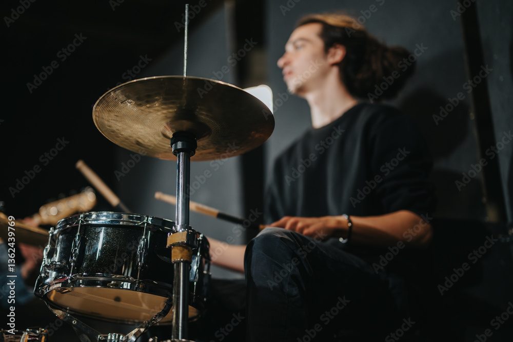 Obraz premium A drummer is engaged in playing drums during a band practice session, creating an energetic atmosphere. The image captures the focus and passion of musical performance.