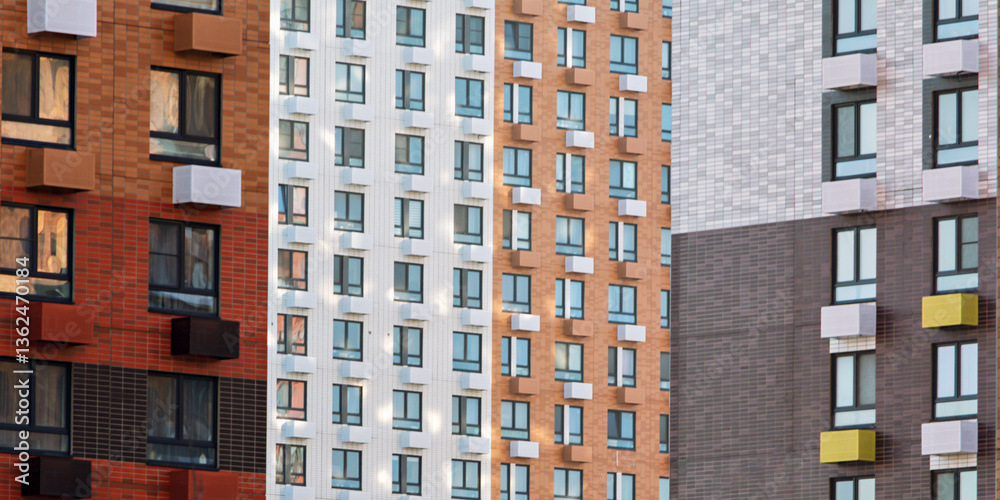 Fototapeta premium Colorful modern apartment building facade with repeating windows and geometric balconies forming abstract urban pattern in daylight.