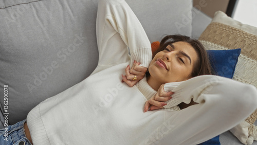 Foto Woman relaxing indoors on sofa with pillows wearing white sweater brunette smili