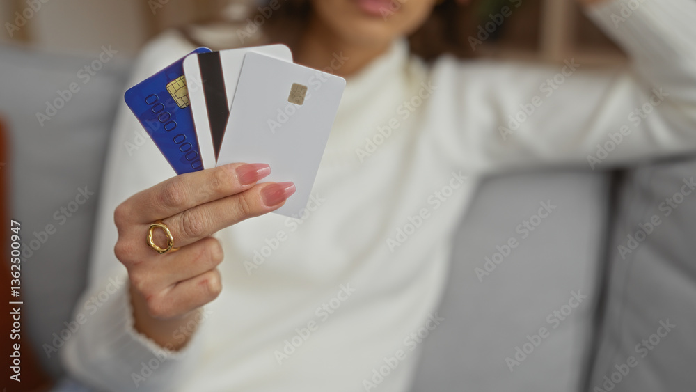 Woman holding credit cards indoors on sofa at home displaying modern lifestyle and financial independence. Woman holding credit cards indoors on sofa at home displaying modern lifestyle and financial independence.