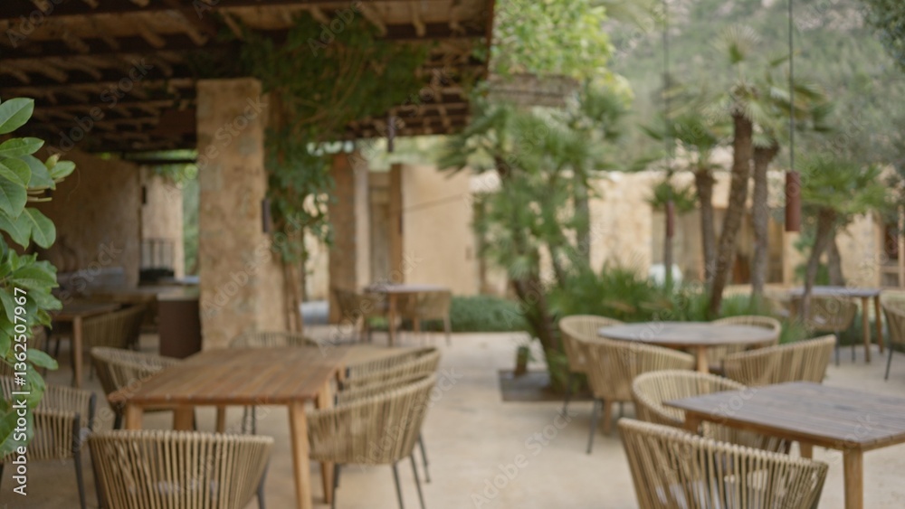 Fototapeta premium Blurred outdoor restaurant terrace featuring wicker chairs and tables under a vine-covered pergola with mediterranean ambiance.