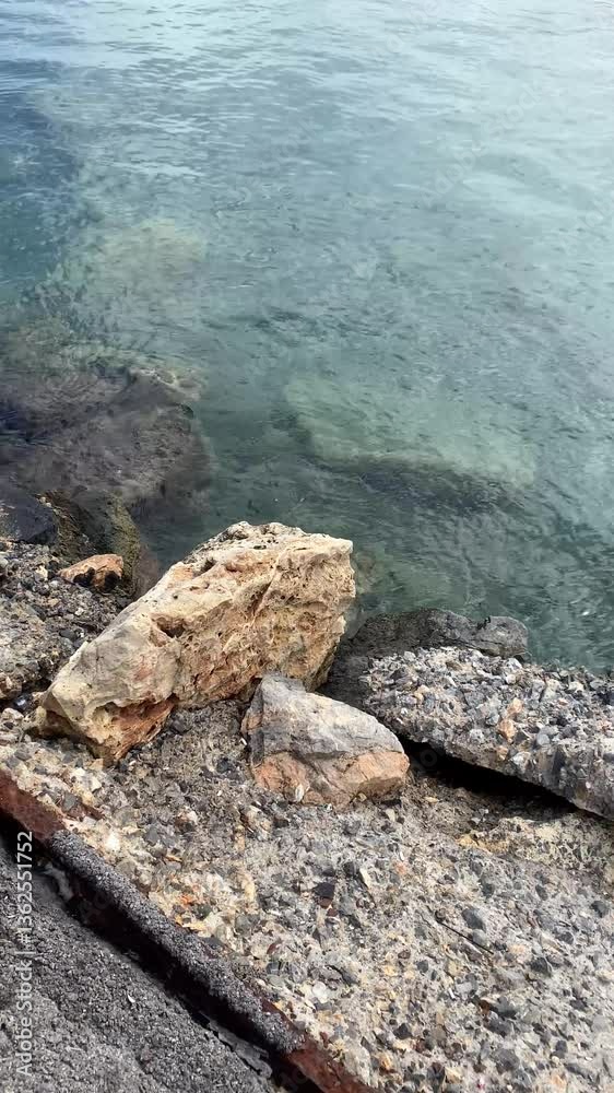 Stony cliff on the seashore, crystal clear water in the sea, vertical video Stony cliff on the seashore, crystal clear water in the sea, vertical video
