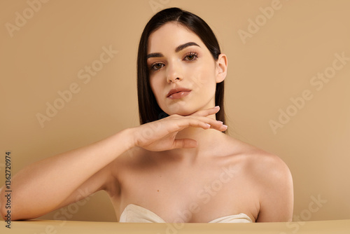 Obraz na plátně Radiant young woman showcasing flawless skin in a serene studio environment