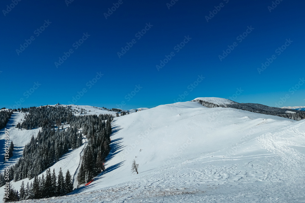 Snow-covered peaks dominate serene landscape of Wölkerkogel, Styria, Austria. Pristine alpine winter beauty and tranquility in remote Austrian Alps. Distant mountain ridges and hills in Lavanttal Alps