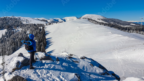 Obraz na płótnie Hiker man on snow-covered peak. Serene winter landscape of Wölkerkogel, Styria, Austria. Dense pine forests. Pristine alpine beauty and tranquility. Remote Austrian Alps. Hills of Lavanttal Alps w salonie