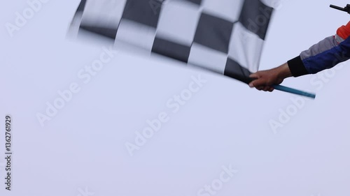 Man holding and waving checkered race flag on finish podium, Finish line and checkered flag, Race flag at the finish line on a race track, Victory achievement success motorsport.