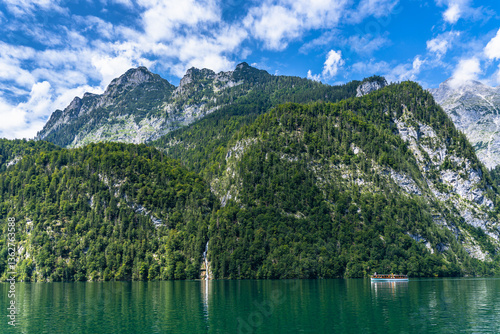 Stunning panorama view of Konigssee Lake with Bavarian alps and Schrainbach waterfall from cruise ship, in Berchtesgaden national park on a sunny summer day, Schoenau, Bavaria, Germany