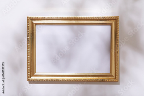 Empty golden picture frame on white wall