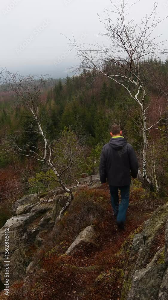 Young man in jacket and with backpack walking through rock landscape in fog misty morning. Explore, alone trip background Young man in jacket and with backpack walking through rock landscape in fog misty morning. Explore, alone trip background