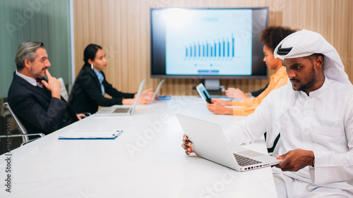 Photography A group of different business people are sitting around a big meeting table in a modern office