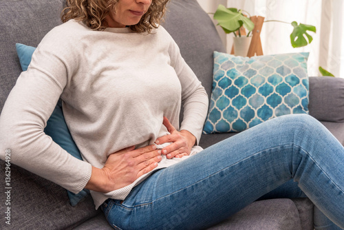 Foto Woman experiencing abdominal pain while resting on a sofa, digestive issues or m