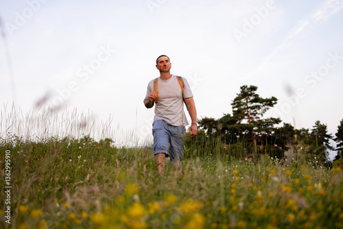 A male tourist is walking across the field.