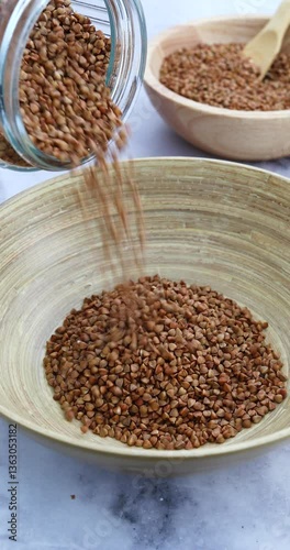A man pours buckwheat from a jar into a bowl