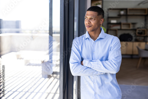 Businessman in blue shirt standing by window, contemplating future opportunities, copy space photo