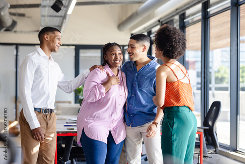 Diverse colleagues in office smiling and chatting during casual diverse team meeting