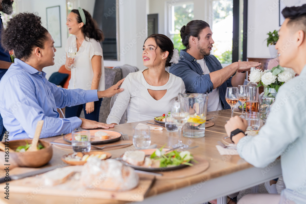Friends enjoying conversation and drinks at elegant small casual wedding reception table, at home Friends enjoying conversation and drinks at elegant small casual wedding reception table, at home