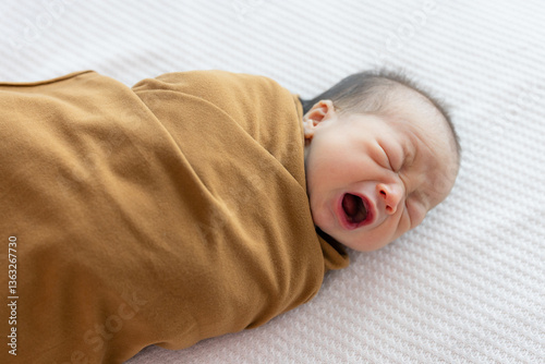 Newborn baby swaddled in blanket crying