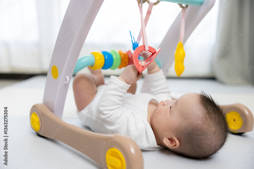 Cute baby playing with hanging toy happily